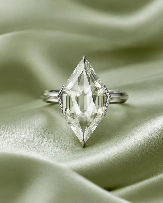 Bague à pierre taille cerf-volant posée sur un satin vert sauge